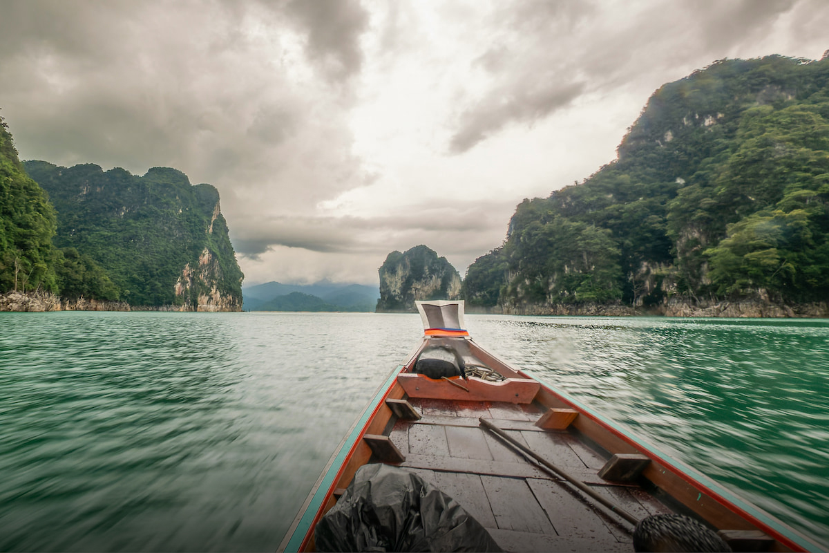 Bow of a small boat approaching karst hills in Thailand