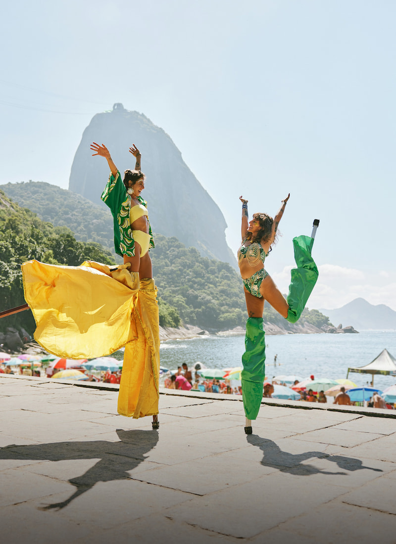 Two women dressed colorfully dancing in front of copacabana beach