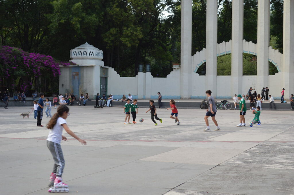 Children playing futbol and skating across the plaza Foro Lindbergh in Parque Mexico in Mexico City